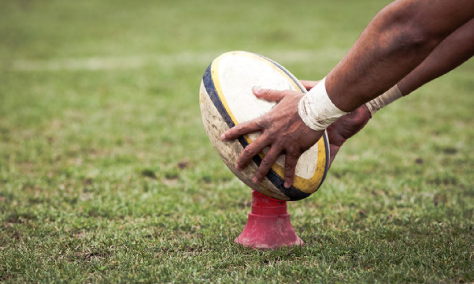 Rugby player placing a ball on a kicking tee